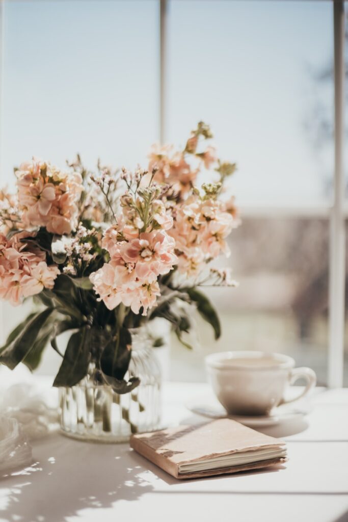 Journal with a handwritten list beside a bouquet of flowers and cozy decor.